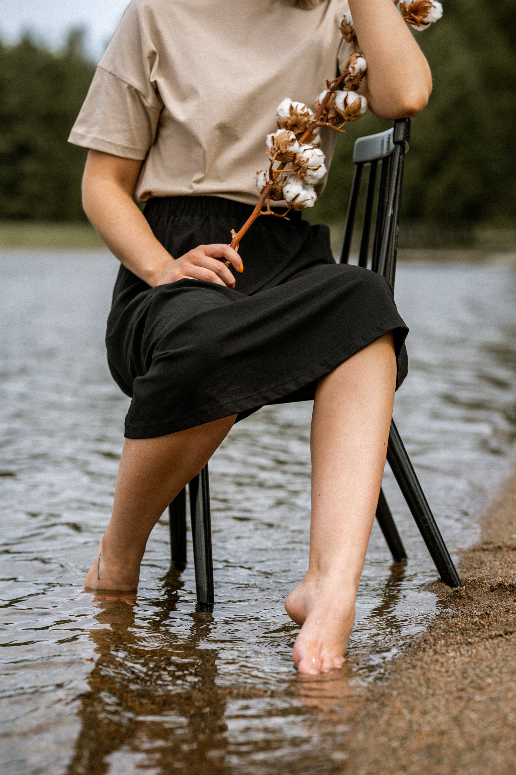 Nainen istuu tuolin päällä vedessä.