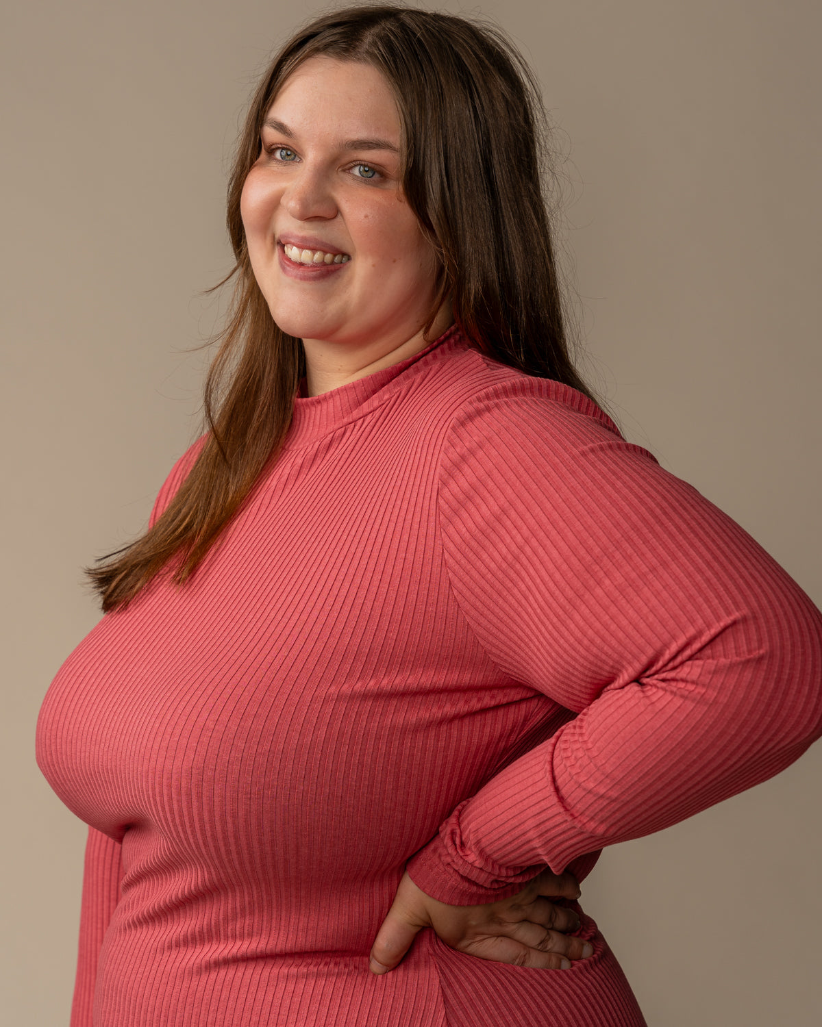 Ribbimekko, marjapuuro in soft pink ribbed fabric displayed by a smiling model wearing a turtleneck and long sleeves.