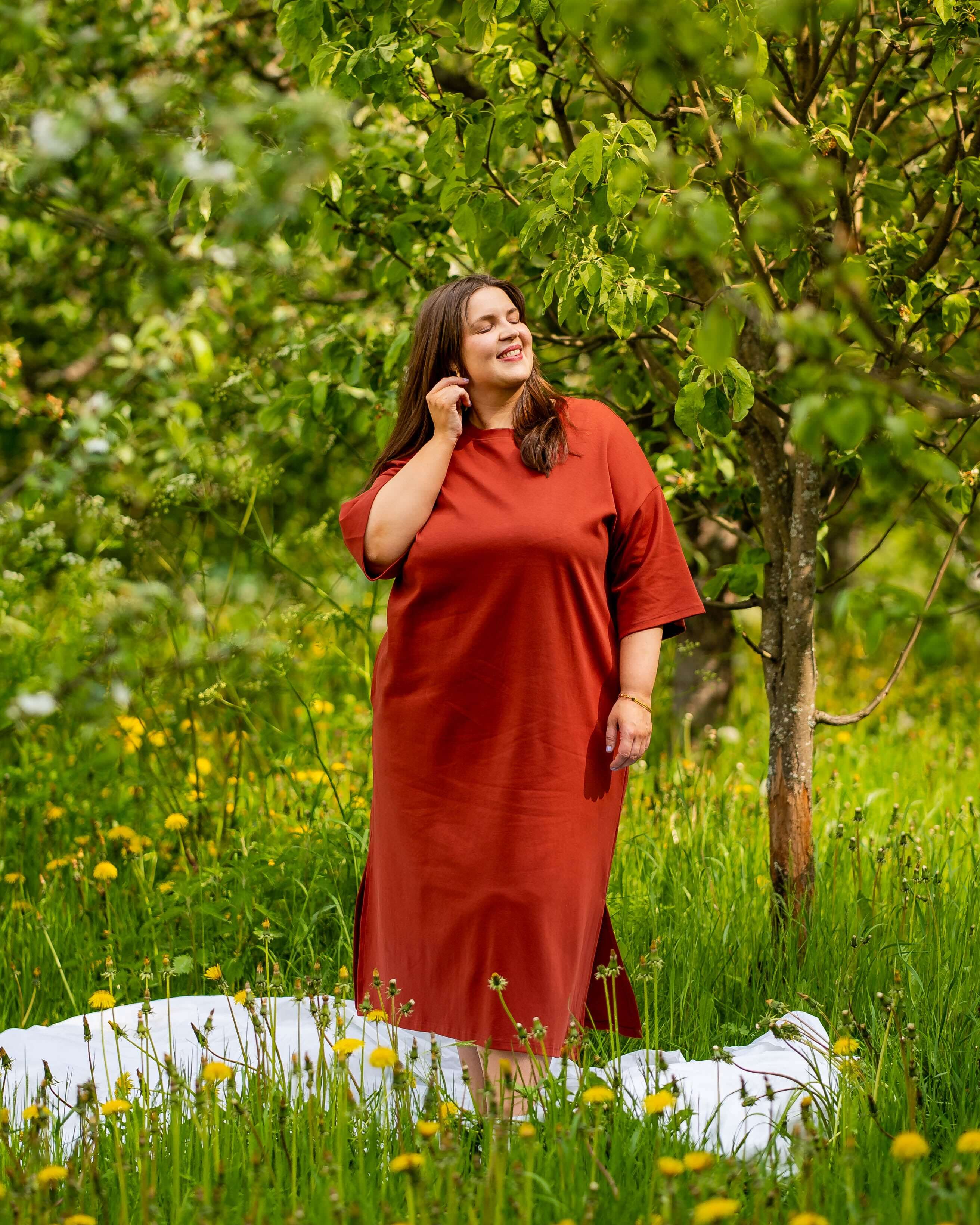Nainen seisoo puun alla päällään Toiveen boxymekko sävyssä mahonki.