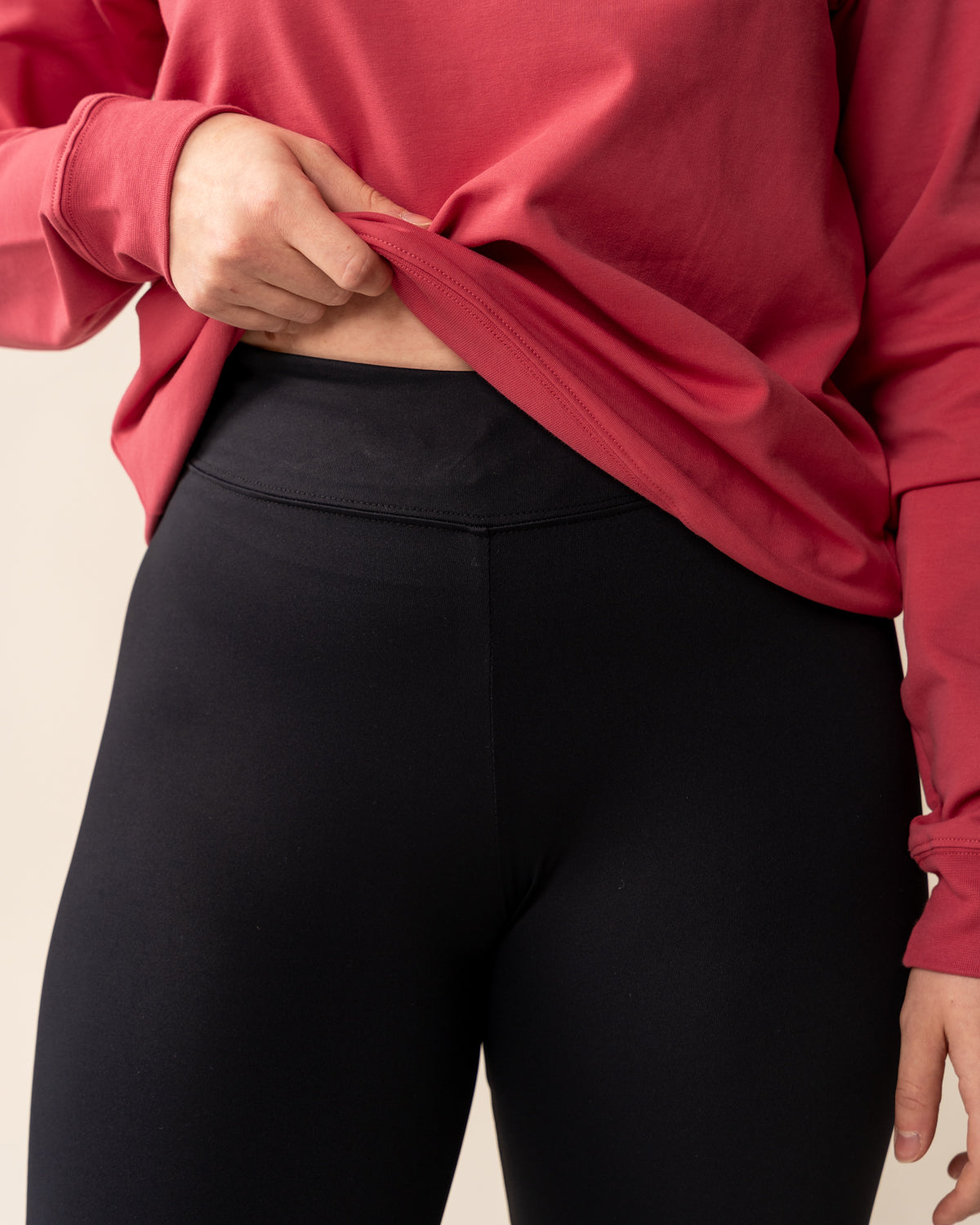 Nainen pukeutuu pitkään mustaan leggingsiin, jossa on kiristysnauha vyötäröllä.